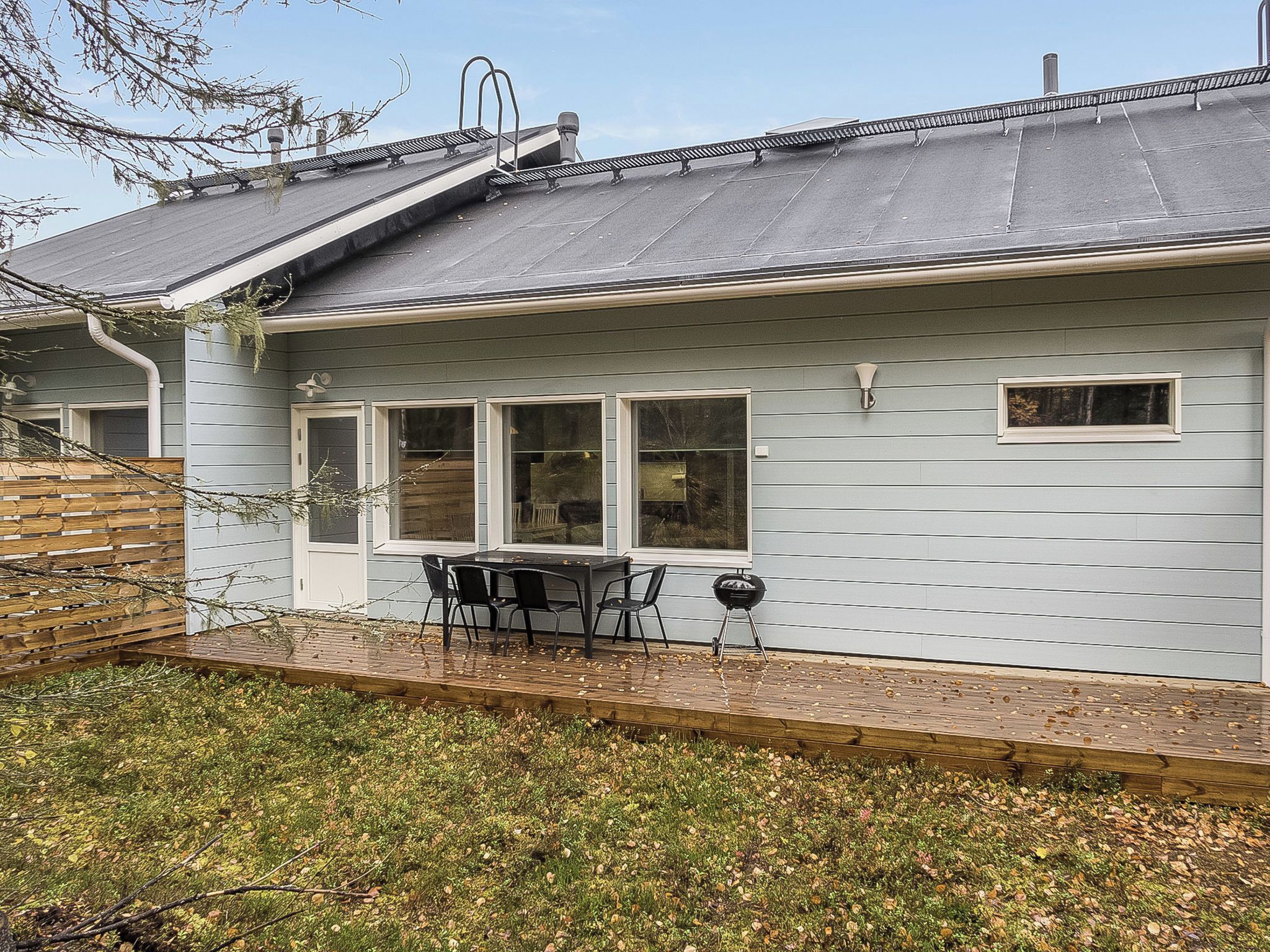 Une maison avec un patio, une table et des chaises, et un barbecue.