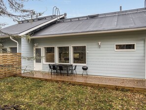 A house with a patio, a table with chairs, and a grill.