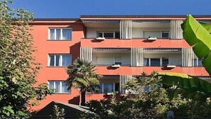 A multi-story building with balconies, air conditioning units, and a red facade.