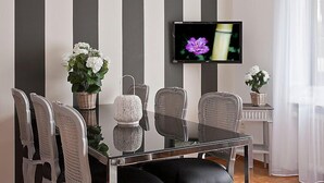 A modern dining area with a glass table, striped walls, and a TV displaying a flower.