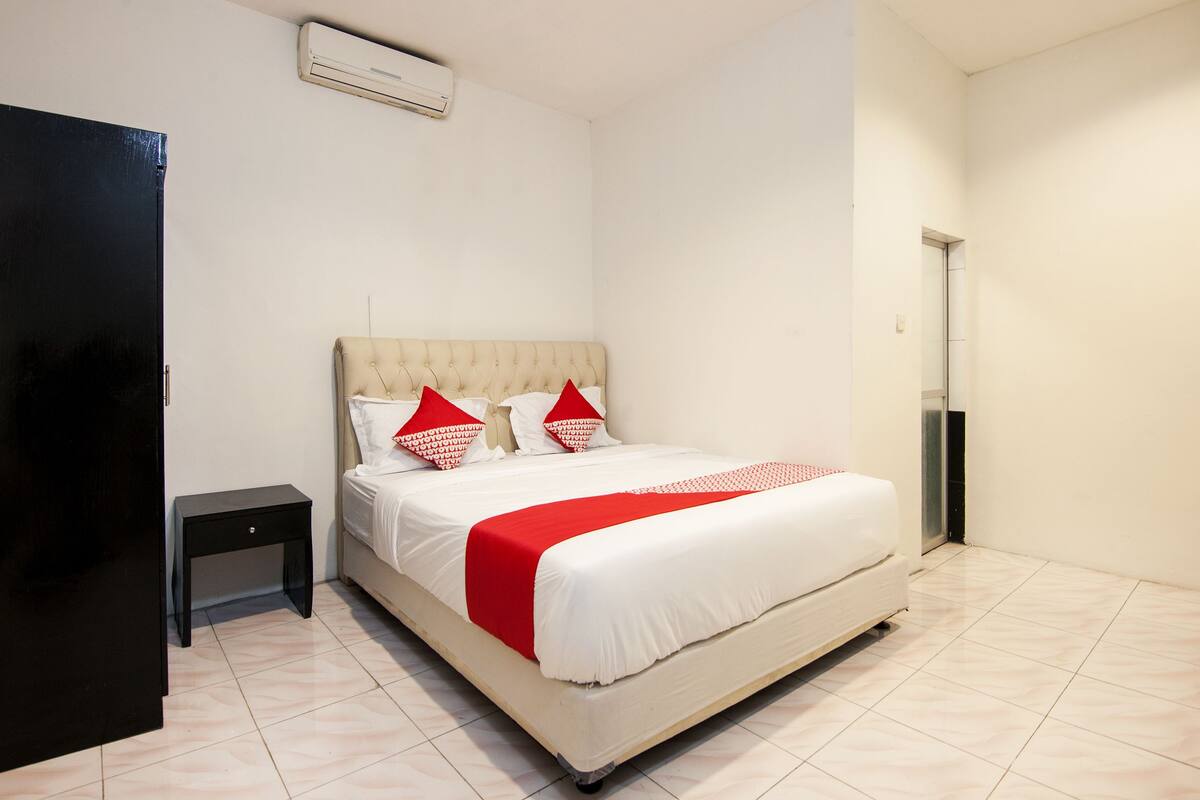 Une chambre d’hôtel avec un lit, une petite table de chevet, une armoire et une porte.