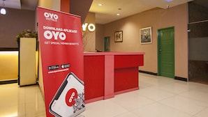 Un espace d’accueil d’hôtel avec un comptoir rouge, une porte verte et une enseigne publicitaire pour les hôtels OYO.