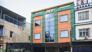 Un bâtiment dont la façade porte l’enseigne « OYO », et qui présente une combinaison de couleurs : vert, orange et bleu.