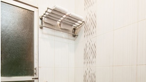 Une salle de bain avec des toilettes blanches, un porte-serviettes et un espace douche.