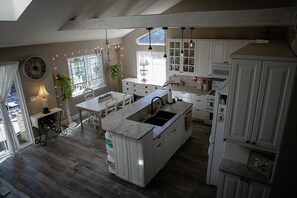 A spacious kitchen with white cabinetry, a large island, and a dining area with a table and chairs. - Bright & Cozy Cottage- Serene Artist’s Home (Lafayette)