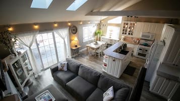 Un espacio habitable amplio con un sofá gris, una mesa de comedor y una cocina con armarios blancos y una isla central.