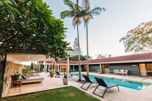 A poolside area with lounge chairs, a barbecue grill, and a covered seating area.