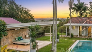 A residential property with a stone wall, a covered patio, a swimming pool, and a view of the sunset. - 🌿 Tin Horse Ranch – Private Byron Hinterland Estate | Pool | Sleeps up to 20 (Pearces Creek)