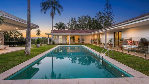 Una casa moderna amb piscina, un porxo cobert i un jardí ben cuidat.