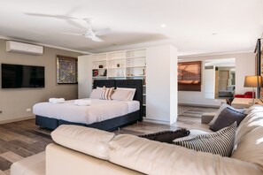 Een moderne slaapkamer met een bed, een plafondventilator, een televisie en een inbouwkast.