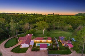 An aerial view of a residential property with multiple buildings, a swimming pool, and a well-maintained lawn.