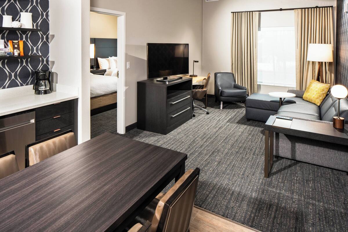Ein Hotelzimmer mit Bett, Fernseher, Schreibtisch, Sofa und Esstisch.