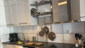 Una cocina moderna con armarios blancos, encimera negra y electrodomésticos de acero inoxidable.