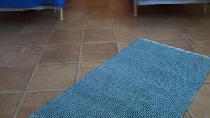 Habitación con dos camas, cada una con cubrecama azul y almohadas estampadas, paredes de madera, un estante pequeño y una única lámpara sobre las camas.