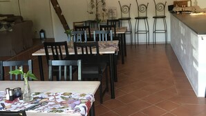 Un comedor con varias mesas y sillas, techo de listones de madera y suelo de baldosas.