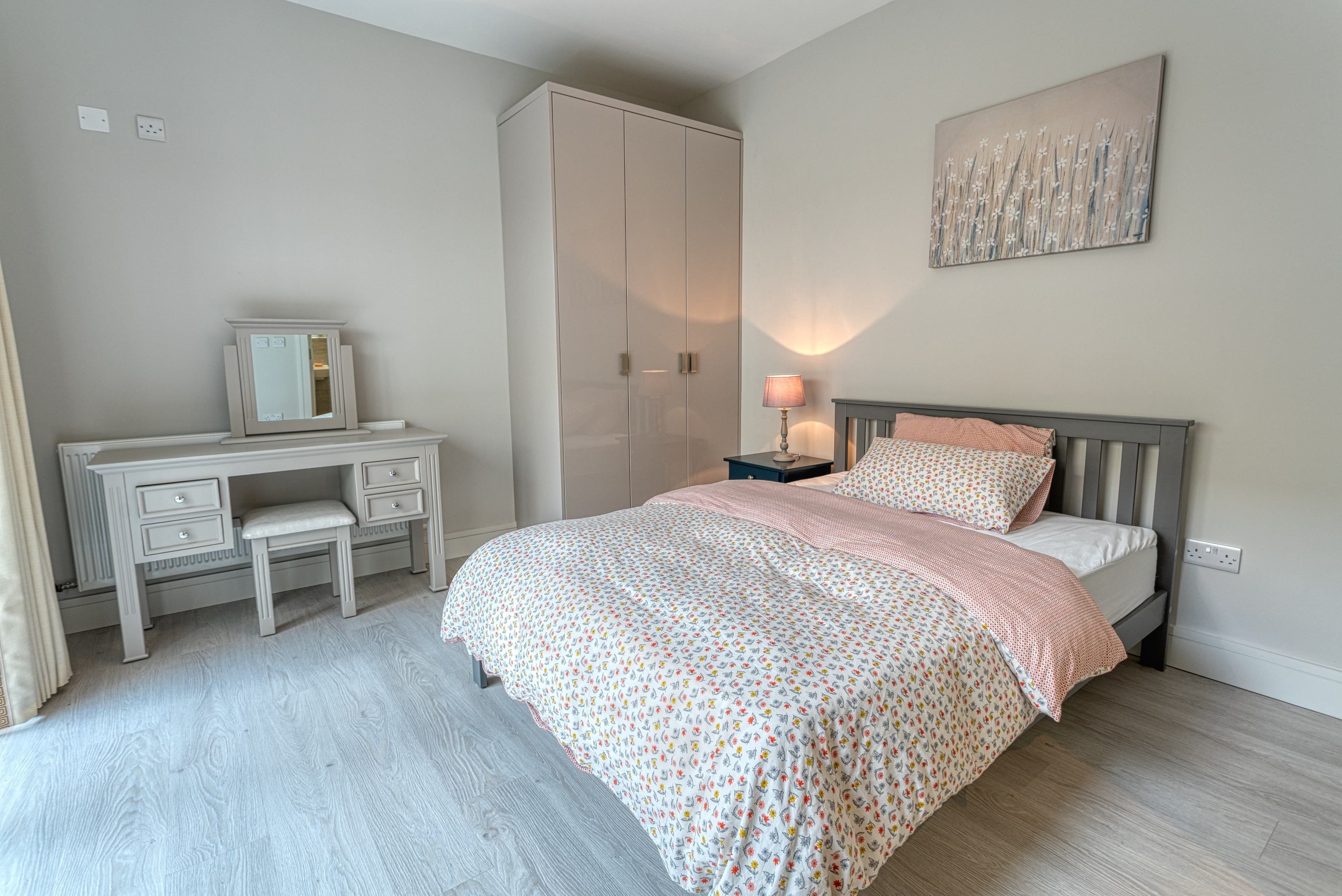 A bedroom with a bed, a dresser, a nightstand, and a wardrobe.