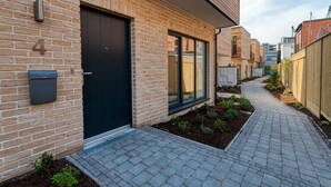 A modern brick building with a black door, a post box, and a narrow paved pathway. - The Larry Mullen Suite - hiphipstay (Dublin)