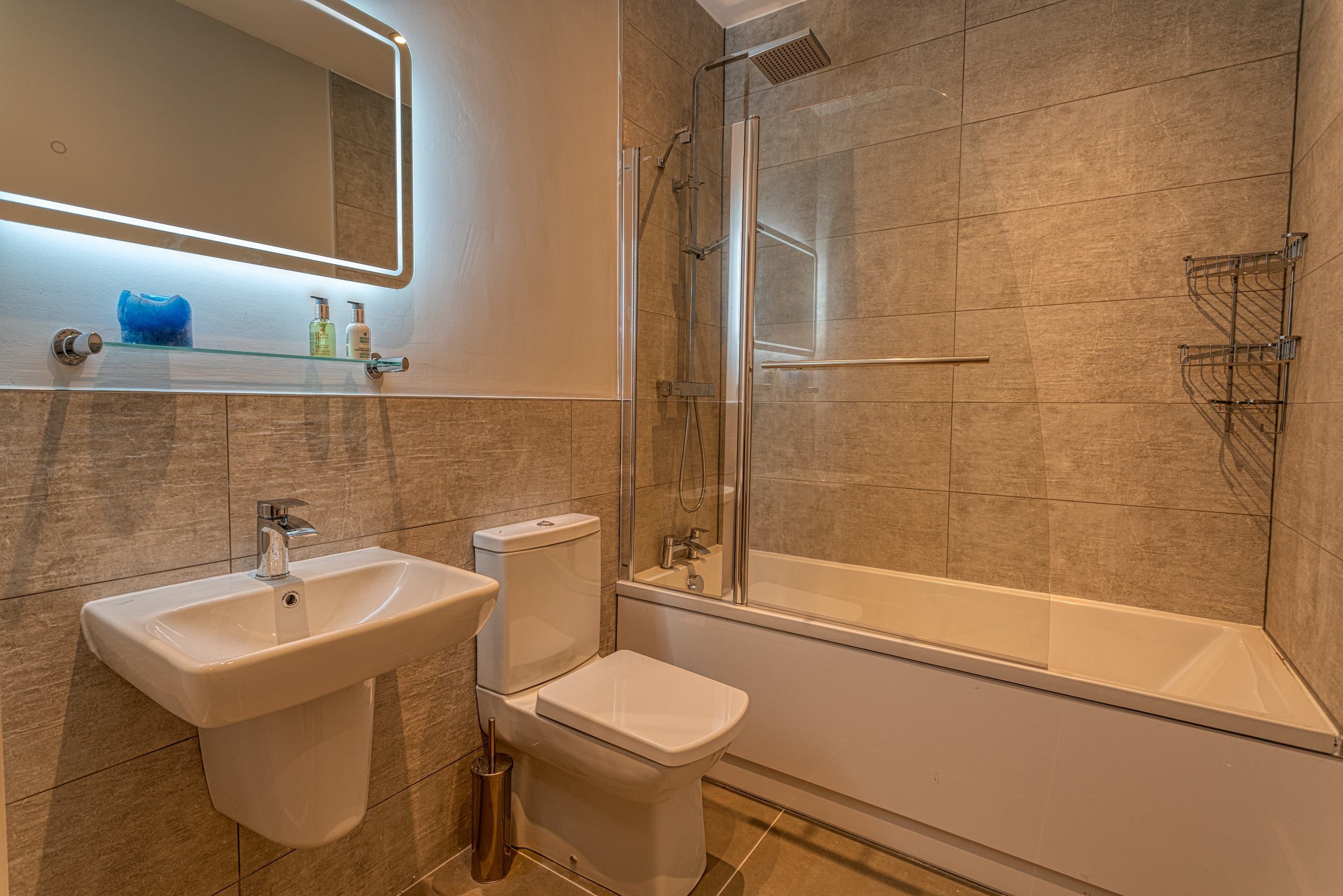 Un baño moderno con ducha de vidrio, lavamanos pedestal y un inodoro.