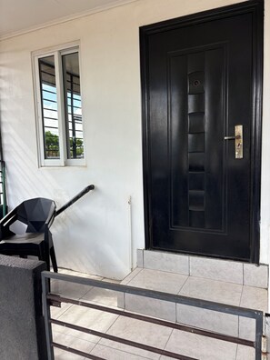 A black door with a keyhole and a window with a metal grille.