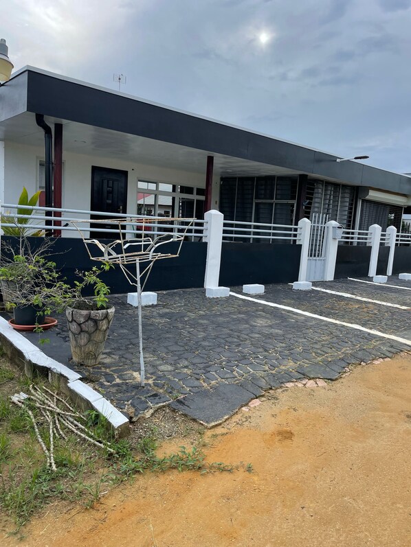 A building with a modern design, featuring a covered entrance area with a black roof and white railings. - DoksaTas Apartements A (Paramaribo)