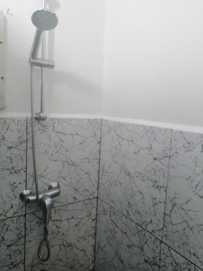 A bathroom with a shower, white tiled walls, and a marble floor. - DoksaTas Apartements A (Paramaribo)