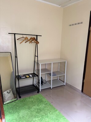 A room with a black metal shelf unit, a green textured rug, and a white shelving unit. - DoksaTas Apartements A (Paramaribo)