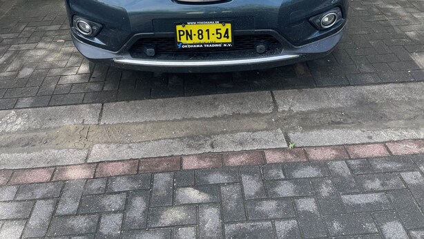 Een Nissan auto geparkeerd op een verharde ondergrond met een kentekenplaat.
