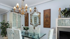 A dining area with a glass table surrounded by patterned chairs, a chandelier, and decorative mirrors. - Stunning apartment on the Golden Mile (Marbella)