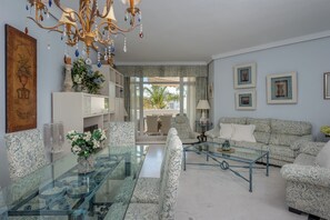 A living room with a glass coffee table, patterned sofa, and a chandelier.