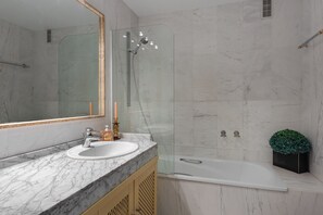 A modern bathroom with a marble sink, a glass-enclosed shower, and a white bathtub. - Stunning apartment on the Golden Mile (Marbella)
