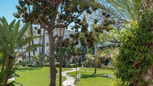 A well-maintained garden with a stone pathway, benches, and various tropical plants. - Stunning apartment on the Golden Mile (Marbella)