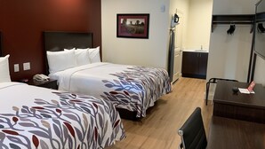 A hotel room with two beds, a desk, a chair, a mirror, a picture on the wall, and a small kitchenette. - Red Roof Inn Houston - Willowbrook (Houston)
