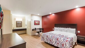 A hotel room with a bed, desk, and a bathroom visible through an open door. - Red Roof Inn Houston - Willowbrook (Houston)
