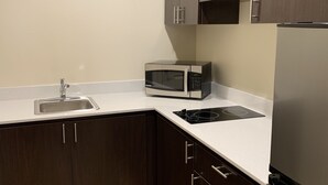 A kitchen with dark cabinets, a microwave, a sink, and a refrigerator. - Red Roof Inn Houston - Willowbrook (Houston)