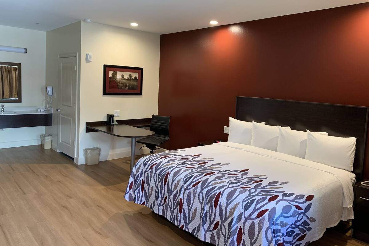 A hotel room with a bed, a desk, and a chair.