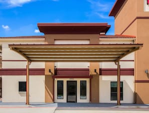 A building with a covered entrance, a flat roof, and a beige facade. - Red Roof Inn Houston - Willowbrook (Houston)