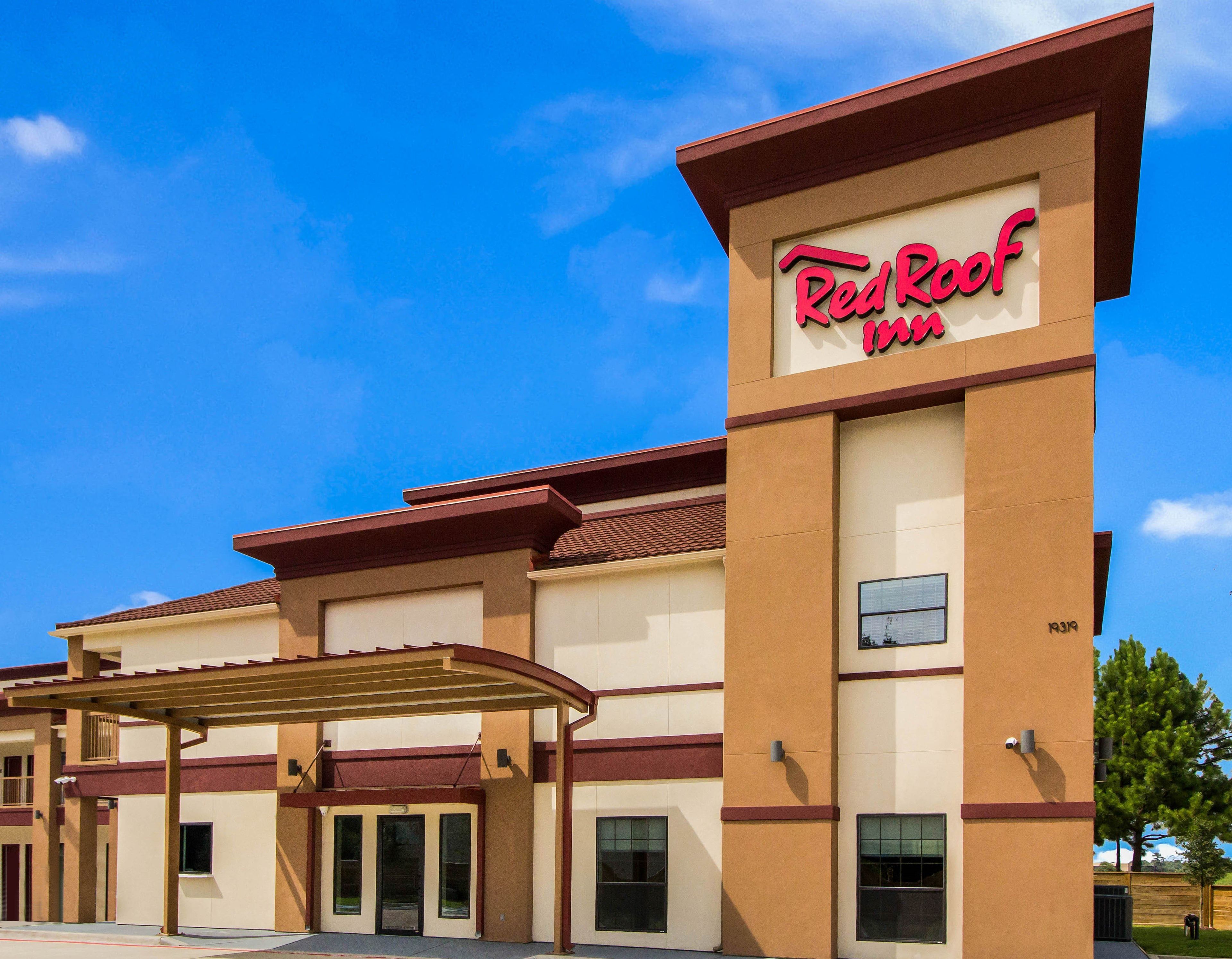 A Red Roof Inn with a covered entrance and a clear blue sky.