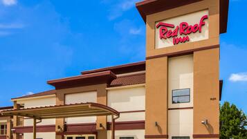 A Red Roof Inn with a covered entrance and a clear blue sky.