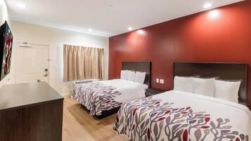 Ein Hotelzimmer mit zwei Betten, einem Schreibtisch und einer Dusche.