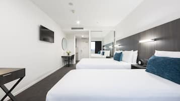 Habitació d'hotel moderna amb dos llits, un escriptori i un mirall.