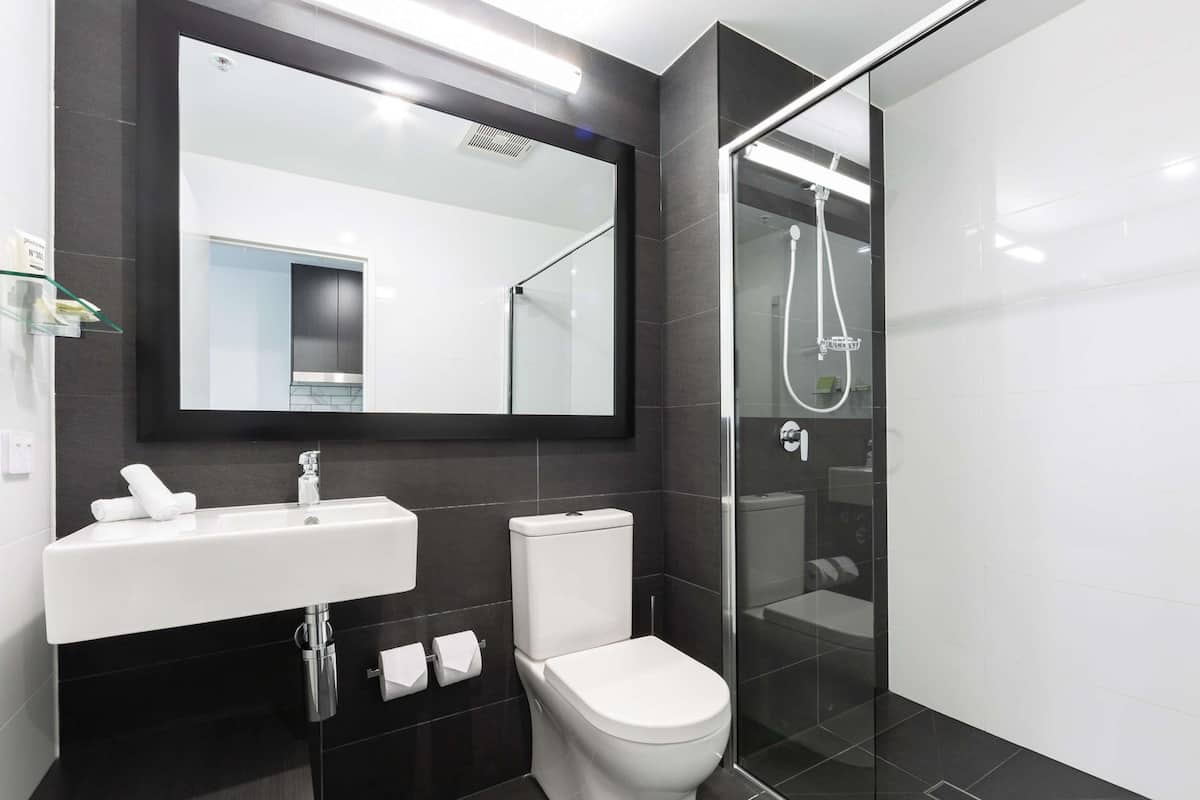 Une salle de bain moderne avec une douche à parois de verre, un lavabo blanc et des toilettes.