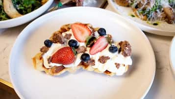 A dessert plate with a pastry topped with strawberries, blueberries, and chocolate pieces.