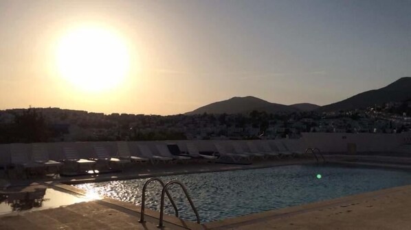 Una piscina al aire libre, sombrillas, sillones reclinables de piscina