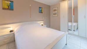 Een slaapkamer met een groot bed, een nachtkastje, een kledingkast en een spiegel.