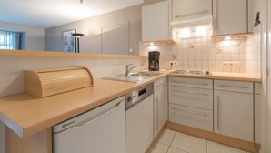 Een moderne keuken met witte kasten, een vaatwasser en een koffiezetapparaat.