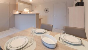 Een eethoek met een tafel gedekt voor vier personen, inclusief borden, bestek en glazen.