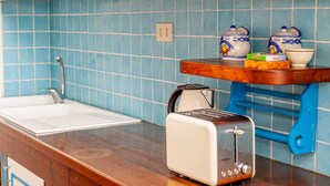 Una cocina con un lavamanos, un tostador y una tetera sobre la encimera.
