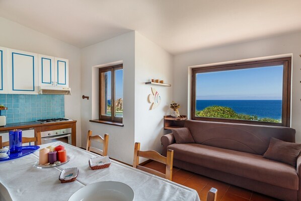 Cucina con vista sul mare, tavolo da pranzo con candele e un divano marrone.