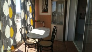Un coin repas comprenant une table ronde et quatre chaises, un rideau à motifs et un meuble avec des portes en verre.