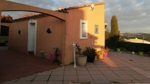 Un bâtiment avec un toit recouvert de tuiles, une porte blanche et un petit balcon orné de plantes en pot.